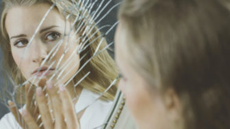 Woman touching broken mirror