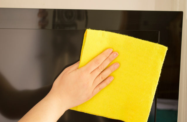 Young woman cleaning a tv flat