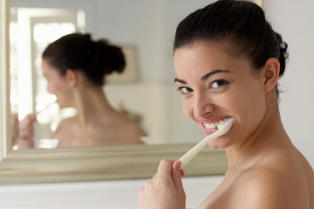 Young woman brushing teeth, close up, portrait