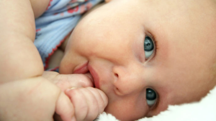 Newborn Infant Girl Laying Down Sucking Her Thumb