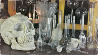 Human skull with bottles on witch table in alchemy laboratory