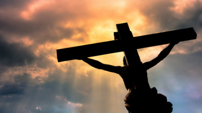 Christian cross with Jesus Christ statue over stormy clouds