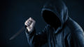 Hooded man with knife in the dark