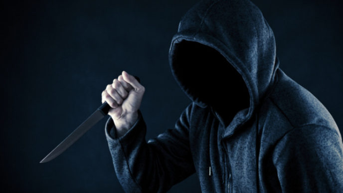 Hooded man with knife in the dark