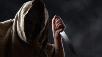 Hooded man in mask with a knife