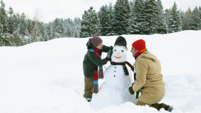 Father and son (8 10) either side of snowman, side view
