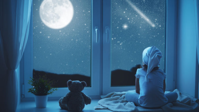 Child little girl at window dreaming and admiring starry sky