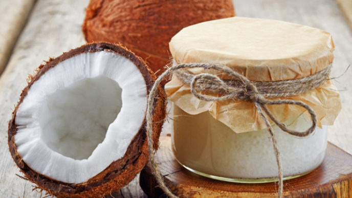 A coconut jar with coconut oil and coconuts sliced in half