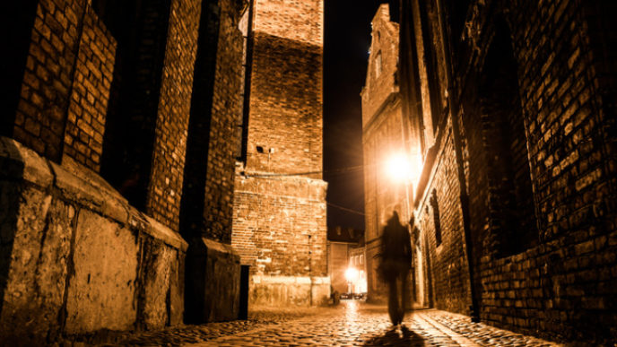 Illuminated cobbled street in old city by night