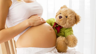 Pregnant woman holding teddy bear to her tummy