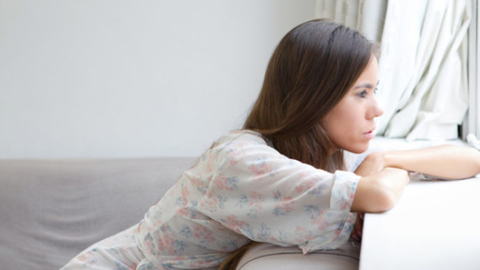 Young woman sitting alone looking out window