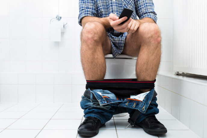 Man In Toilet Using Cellphone