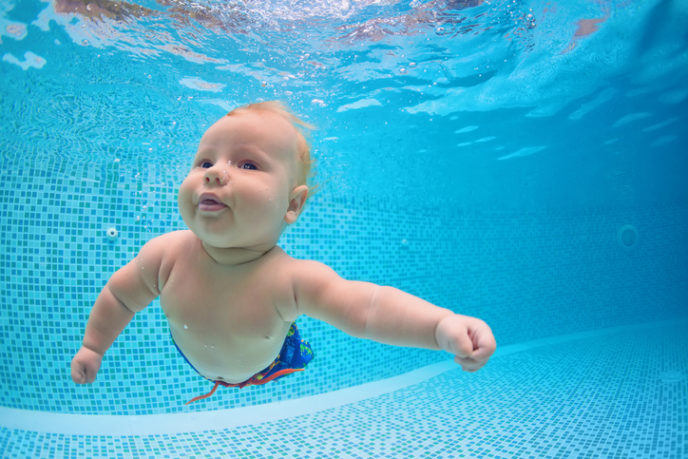 Little baby dive underwater with fun in swimming pool