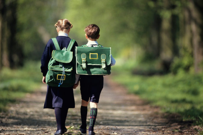 Boy (6 7) and girl (8 9) going school through forest, rear view