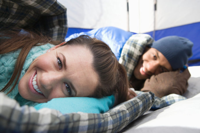 Young couple lie in sleeping bags in a tent