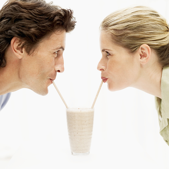Young couple drinking a milkshake from a glass with straws