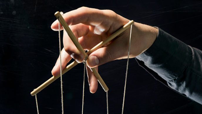 Concept on a theme: the manipulation, the dictator, dependency, slavery, etc. Dictator's arm holds strings for manipulation on black background.