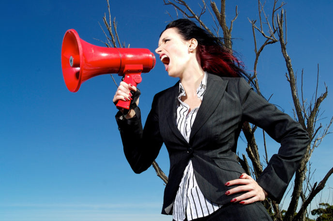 A stock photograph of a beautiful woman yelling into a mega phone.
