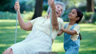 Side profile of a granddaughter pushing her grandmother on a swing