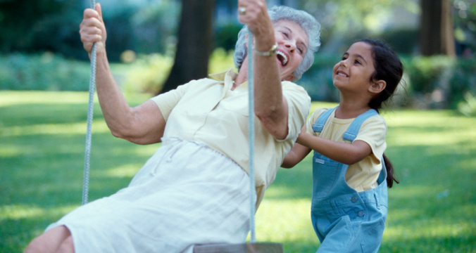 Side profile of a granddaughter pushing her grandmother on a swing