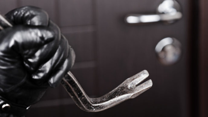 Burglar hand holding crowbar break opening door