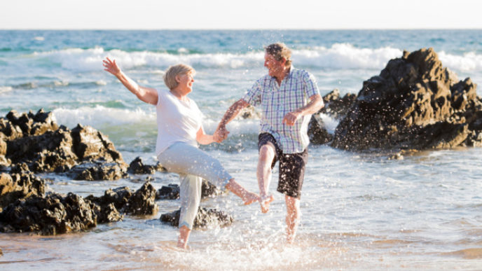 Lovely senior mature couple on their 60s or 70s retired walking happy and relaxed on beach sea shore in romantic aging together and retirement husband and wife lifestyle concept