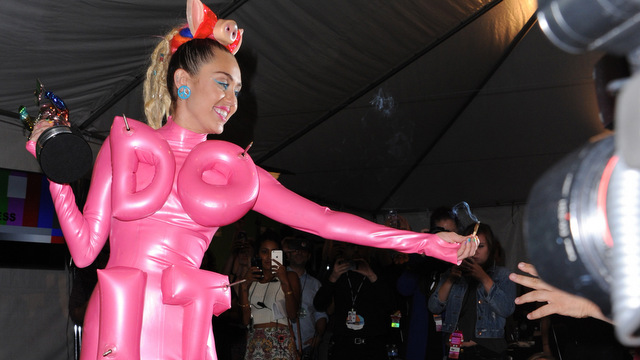 FILE - In this Aug. 30, 2015 file photo, Miley Cyrus passes a lit joint to a photographer in the press room at the MTV Video Music Awards in Los Angeles. Despite commercials preaching to young adults that drugs are bad for you, during the recent MTV Video Music Awards, drugs were just as popular as music. Drugs were mentioned at least six times during the live awards show, hosted by its main pusher, Miley Cyrus. (Photo by Richard Shotwell/Invision/AP, File)