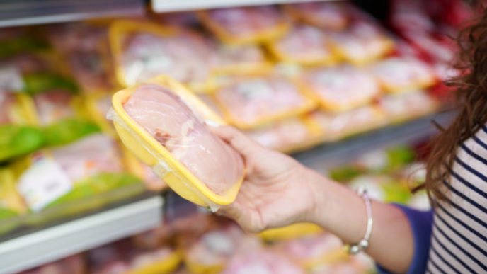 Meat in food store . Woman choosing packed fresh chicken meat in supermarket