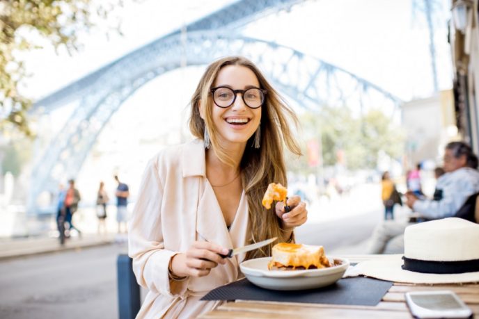 Woman with francesinha meal in Porto city
