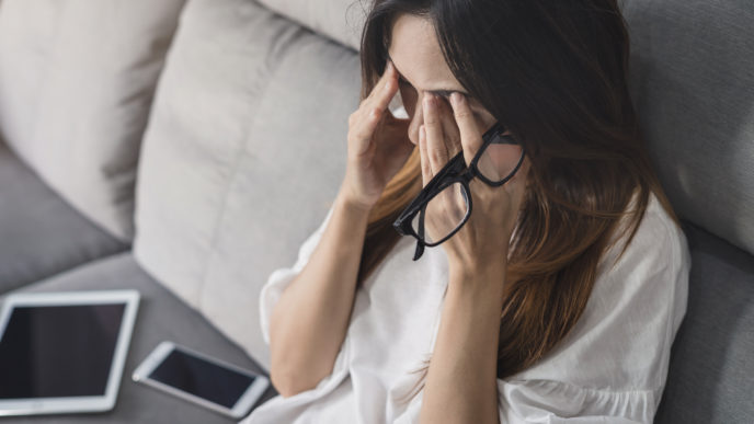 Young woman take off her glasses and siiting on sofa