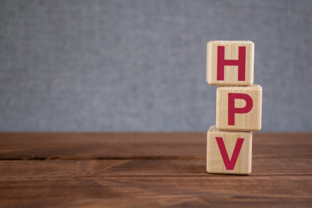 HPV (human papilloma virus) acronym on wooden cubes on dark wooden backround. Healthy care and medical concept.