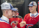 NHL Draft Hockey Juraj Slafkovský (vpravo) zo Slovenska pozdravuje krajana a kolegu draftu Montreal Canadiens Filipa Mesára, vľavo, ako sa na štvrtkové prvé kolo draftu hokejovej NHL v Montreale pozerá Šimon Nemec, tiež zo Slovenska a z New Jersey Devils