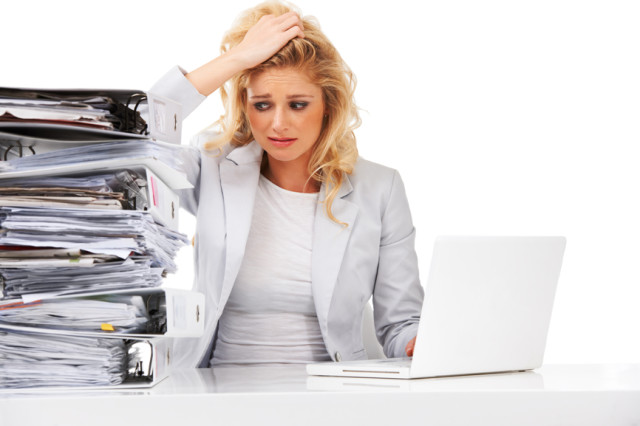 An overworked businesswoman looking anxiously at a pile of files next to her - Isolated