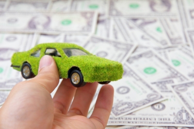 Hračkárske zelené autíčko pri hŕbe dolárov