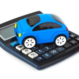 Modré hračkárske autíčko položené na kalkulačke