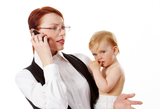 Portrait of business woman holding her small daughter while speaking on the phone