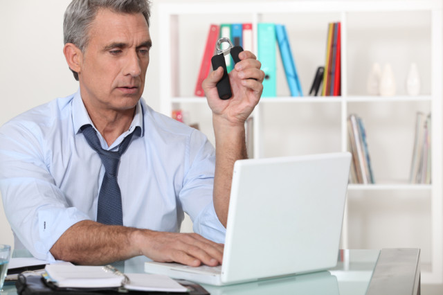 Man squeezing hand grippers while reading an e-mail