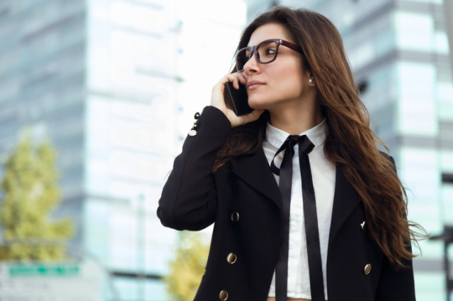 Portrait of beautiful young businesswoman using mobile phone in the street.