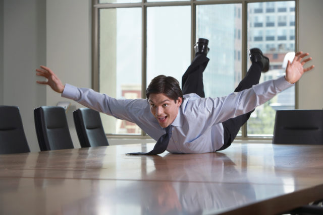 Playful Businessman Laying on Table