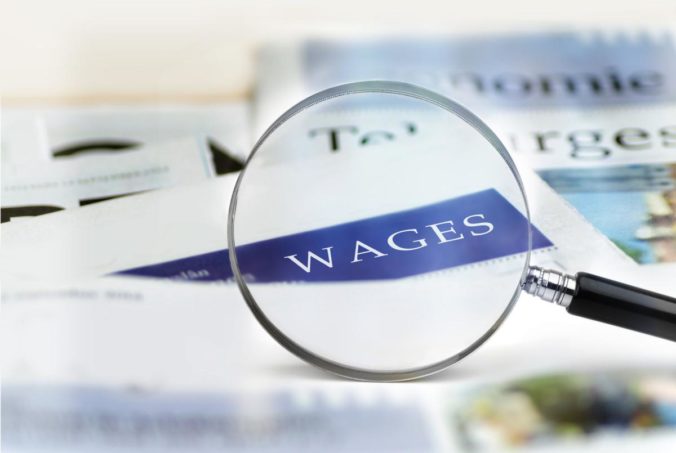 Wages Headline through magnifying glass.