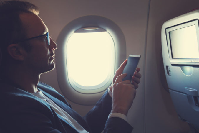 Man using smartphone in the airplane.