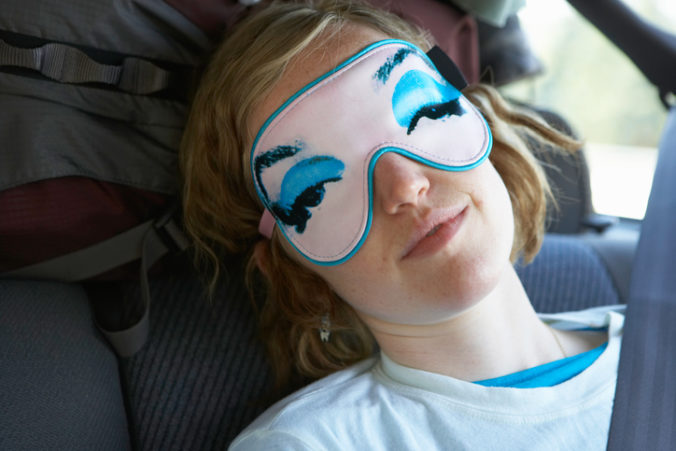 Young woman wearing eye mask in car