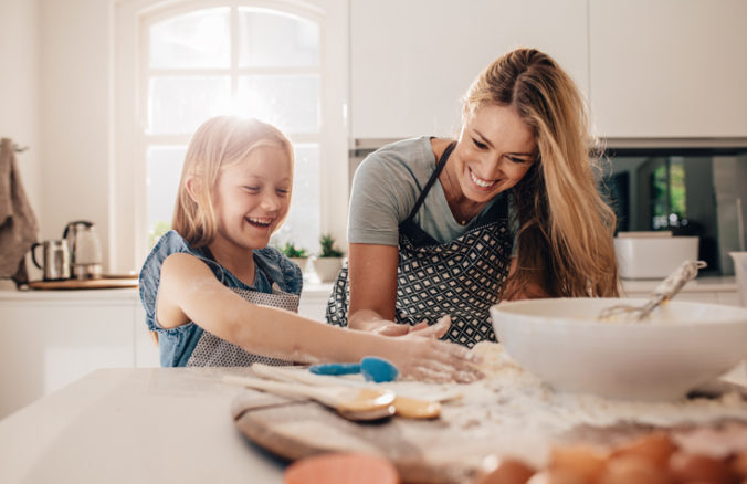 Happy young girl with her mother making dough