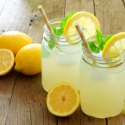 Mason jar glasses of homemade lemonade on rustic wood