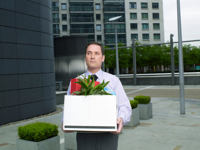 Businessman carrying box containing plant and files on street