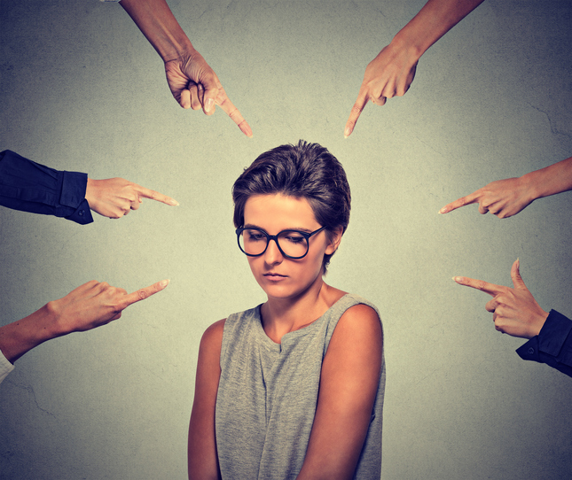 Embarrassed woman looking down many fingers pointing at her