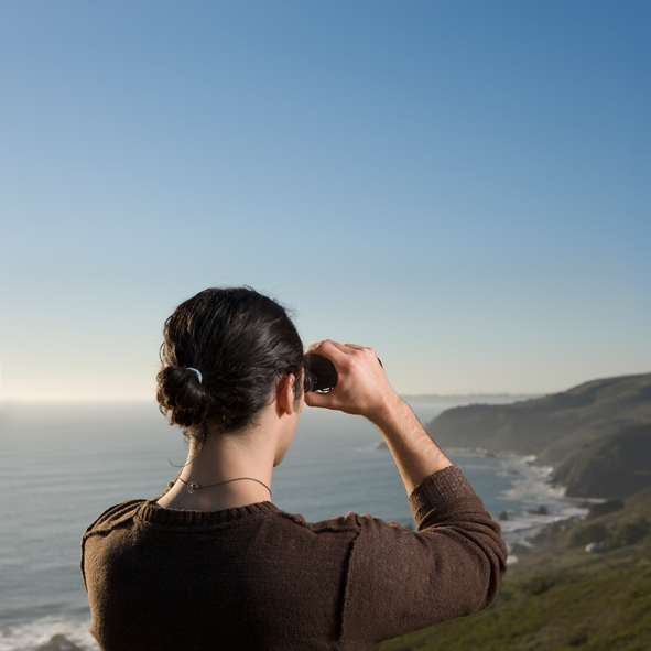 Woman using binoculars at the coast