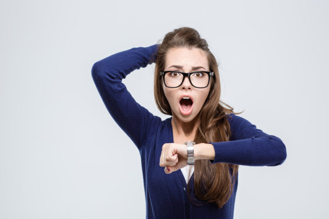 Woman holding hand with wrist watch and looking at camera