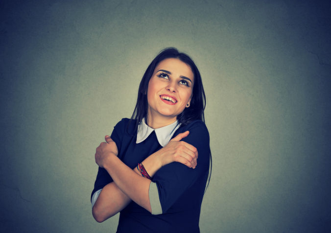 Confident smiling woman holding hugging herself