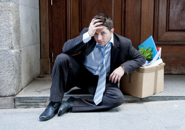 Frustrated business man on street fired carrying cardboard box